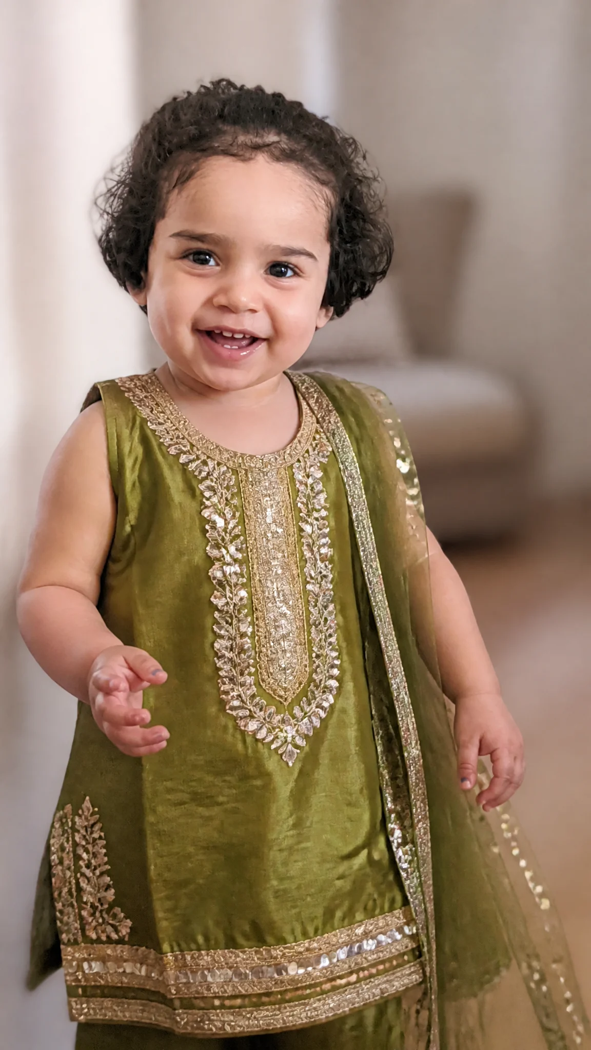 A joyful toddler stands in a brightly lit indoor space, w...